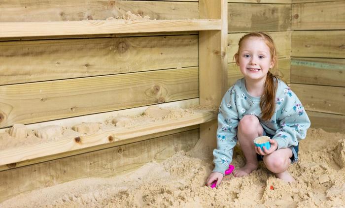 girl playing in sand pit